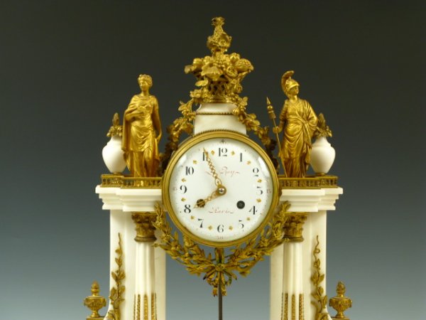 A LE ROY BRONZE DORE' & MARBLE PORTICO CLOCK: An exceptional French example of bronze dore' and white marble with classical gilded bronze figures atop the portico area - a garland draped urn of gold-covered bronze fruit between them. The 5.75 inc