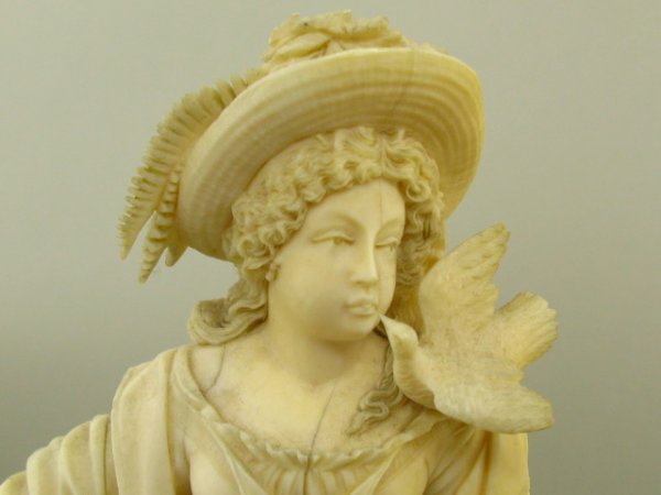 EUROPEAN CARVED IVORY FIGURE OF WOMAN WITH DOVES: Stands 7.75 inches plus 3.75 inch smooth finished pedestal, marvelously detailed figure with special attention to face, hair and feathered hat, dress, shoes and rooster.