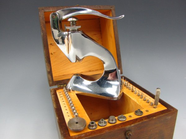 AN ANTIQUE WATCH MAKER'S STAKING SET: A friction jewelling tool, missing two changeable heads, in a 6.5 x 5.5 x 5 inch wooden storage box.