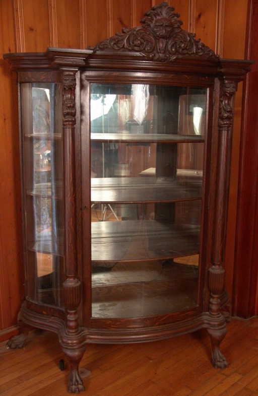 AN AMERICAN OAK CURVED GLASS LION HEAD CHINA CABINET - AN AMERICAN OAK CURVED GLASS LION HEAD CHINA CABINET