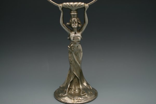AN ART NOUVEAU FIGURAL SILVERED METAL TABLE MIRROR: Silver finished figure holding oval mirror, measures 16.75 x 7.75 inches.
