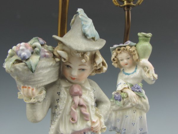 PAIR OF CORDEY FIGURAL LAMPS WITH BOY AND GIRL: Matching pair of lamps with porcelain/ceramic boy and girl carrying baskets and jars, both stand approximately 24 inches to top of acorn finials, ornate bases with gilt trim.