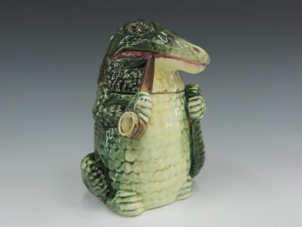 MAJOLICA FIGURAL HUMIDOR OF STANDING ALLIGATOR: Humorous figure of a standing alligator with a pipe in one hand, his tail in the other, measures 6.75 inches, incised 871 to bottom.