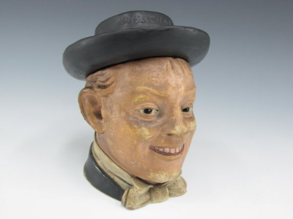 FIGURAL HUMIDOR WITH RESCHAL MAN IN HAT: Indistinct incised signature on bottom, figure of man in bow tie, lid hat reads "Reschal." Measures 6 inches tall.