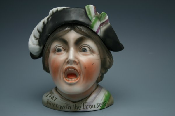 FIGURAL HUMIDOR WITH SUFFRAGETTE THEME: Caricature shrieking humidor with suffragette yelling, "I Say down with the Trousers." Purple, white and green sash and hat ribbon, the colors of the Woman's Congressional Union (headed by Alice Paul)