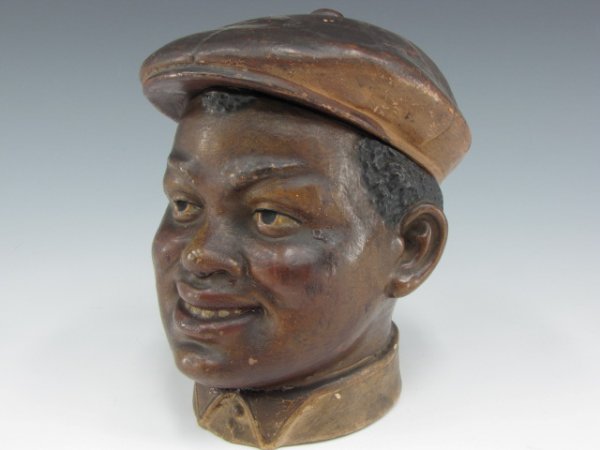 AUSTRIAN TERRA COTTA HUMIDOR WITH BLACK MAN IN CAP: Hand incised "8141 BB" to bottom, depicts young black man wear a cycling cap, measures 6 inches tall.