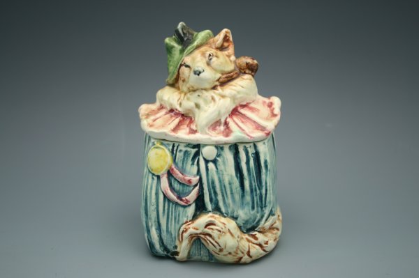 MAJOLICA FIGURAL HUMIDOR WITH FOX DRESSED AS CLOWN: Comic figure of a fox dressed as a clown, incised numbers to bottom, measures 5.25 inches.