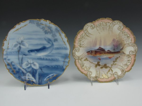 TWO ANTIQUE LIMOGES FISH PLATES: Image of a fish against pink and gilt scalloped border, marked blue and green Limoges marks on verso 9-3/8 inches diameter, plus a flow blue like technique with swimming fish among lilies with gilt hi
