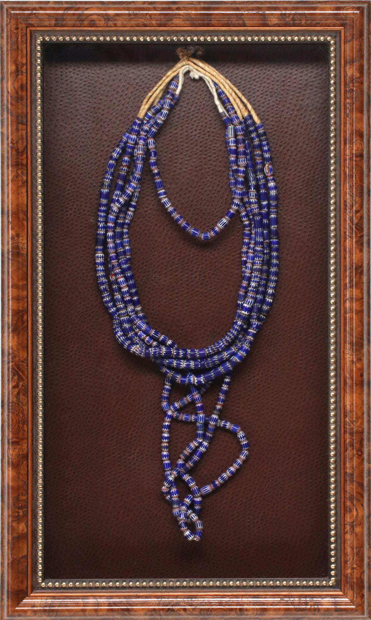 A NECKLACE OF MORE THAN 500 VENETIAN CHEVRON TRADE: The collection of barrel shape trade beads ranging in size from approximately 6 mm to 10 mm range on a twisted twine and displayed in a nice shadow box frame. Frame measures 24.5 x 14.75 inches. We ha