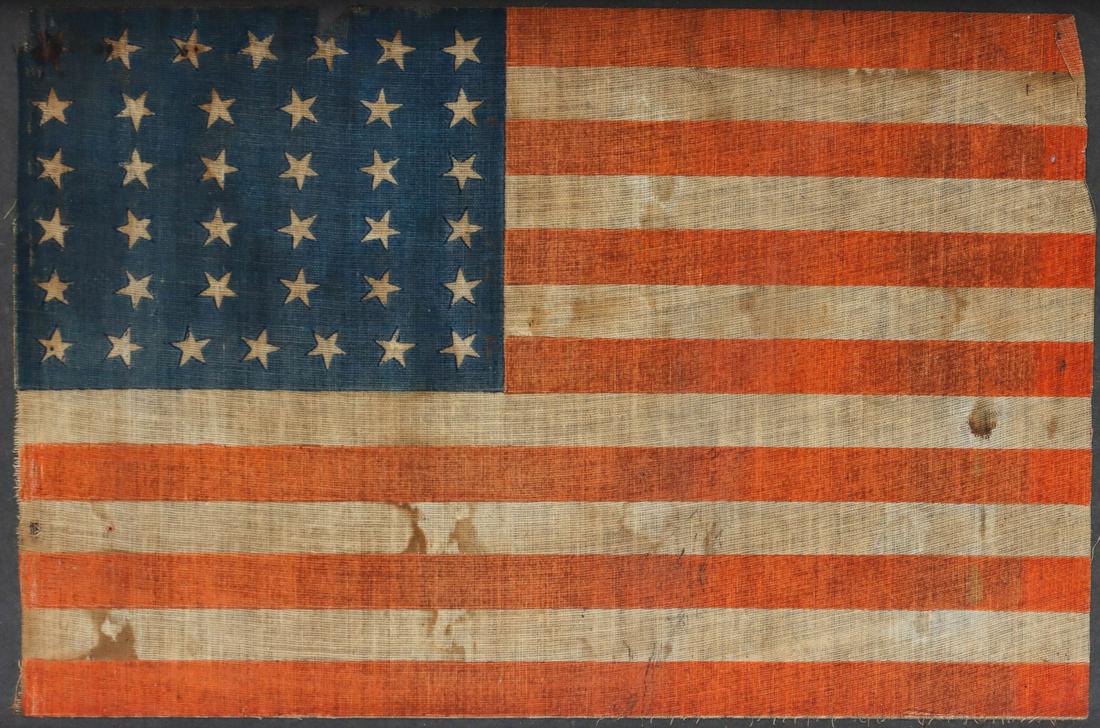 A 38-STAR PRINTED MUSLIN AMERICAN PARADE FLAG C. 1877: A star was added to the United States flag in 1877 for the admission of Colorado and was to last until 1890. Flag measures 9 x 13.25, the frame is 13 x 18.75 inches. We happily provide seamless in-hou