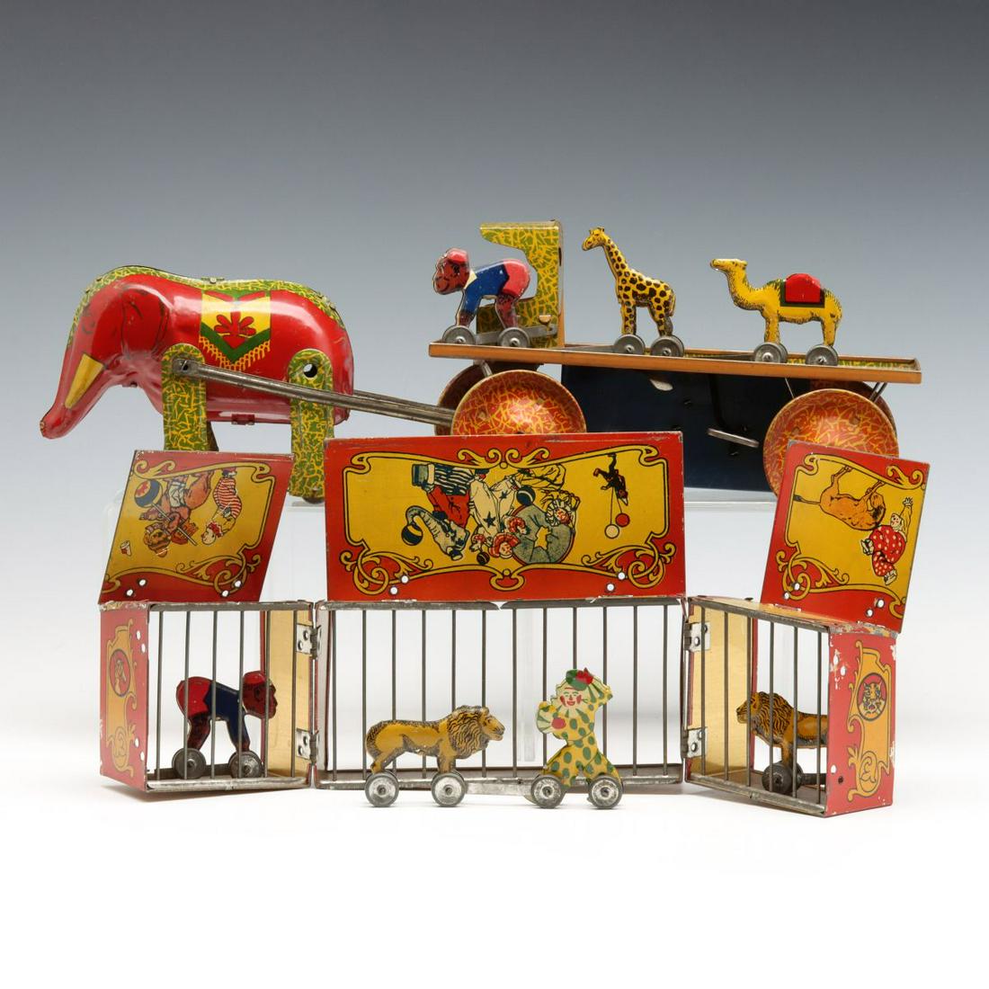 A LINDSTROM NINE PIECE LITHOGRAPHED TIN CIRCUS TOY SET: The elephant-drawn wind-up wagon with fold-out cages and various animals on wheels that can be connected to create a procession are attributed to Lindstrom Toy and Tool Co of Bridgeport, Connecticut, 