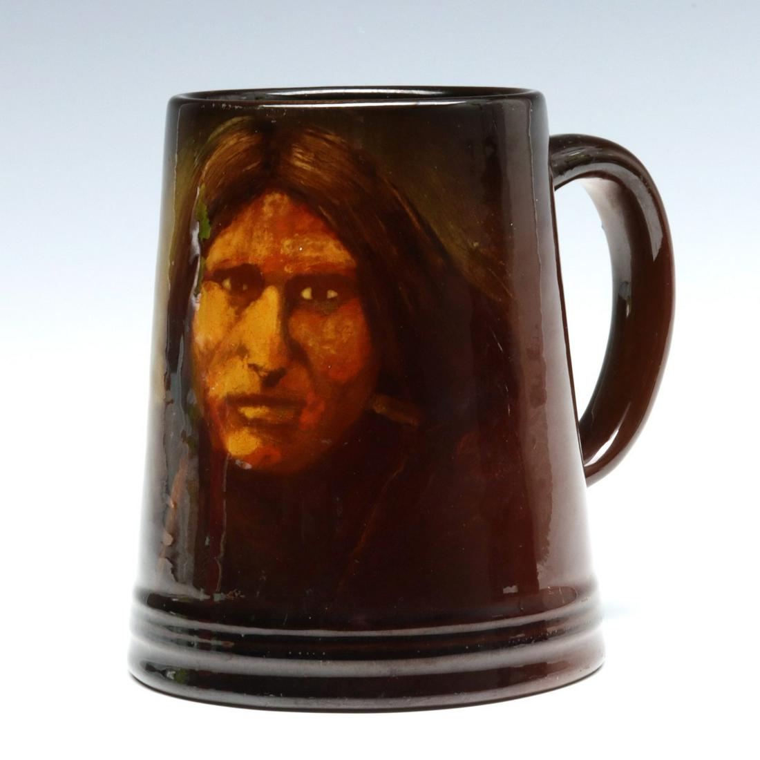 A ROOKWOOD POTTERY MUG WITH NATIVE AMERICAN PORTRAIT: Edward Timothy Hurley (1869 - 1950) 1900 The Rookwood standard glaze mug is painted with the portrait of a Native American identified as LITTLE SOLDIER (UTE) in scratched lettering on the base along w