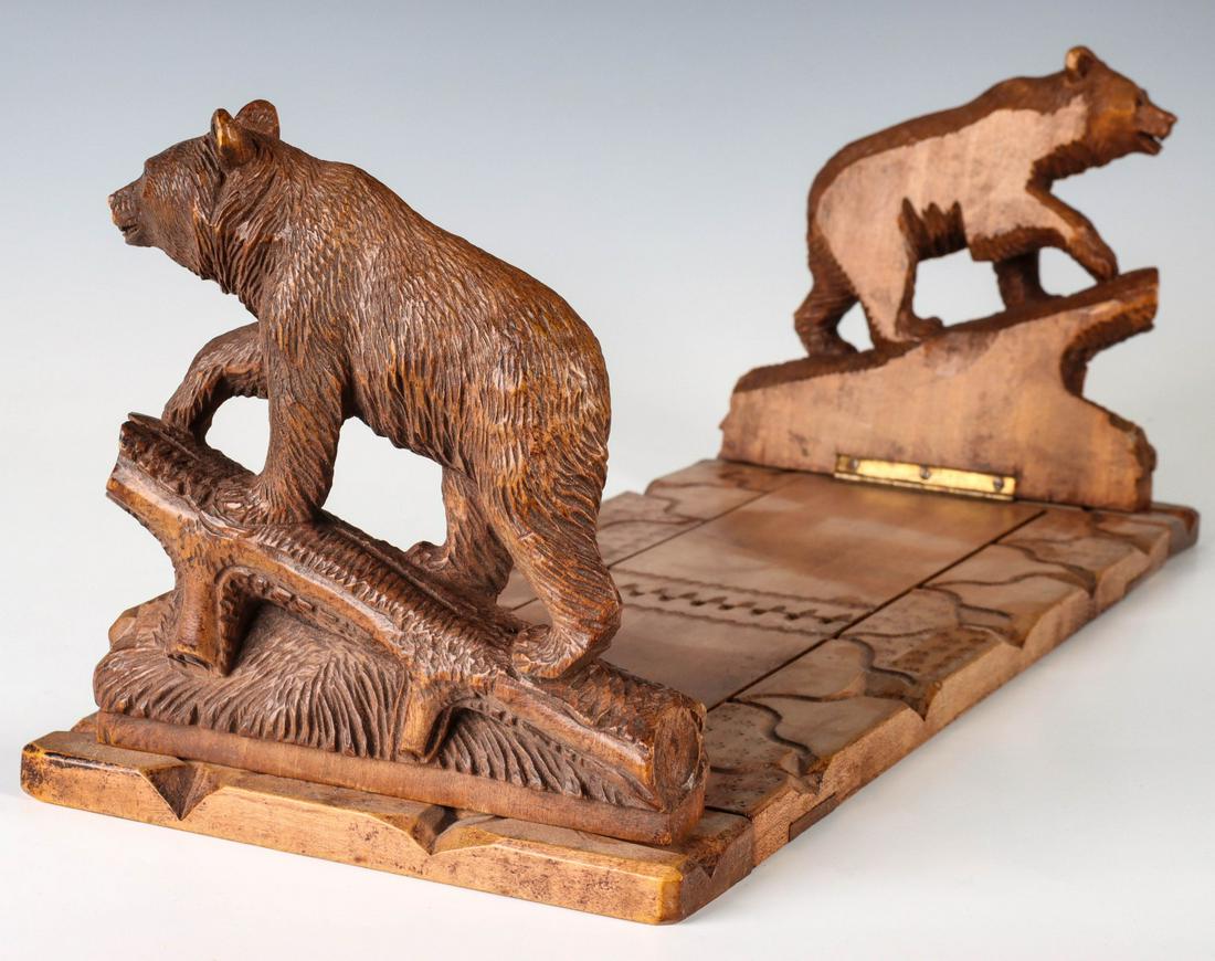AN EARLY 20TH C BLACK FOREST BOOK STAND WITH BEARS: The nicely carved bears atop logs on either end of a sliding book stand, each bear is hinged to fold inward and set with inlaid glass or black tack eyes. Measures 6.75 x 17 x 7 inches. We happily prov