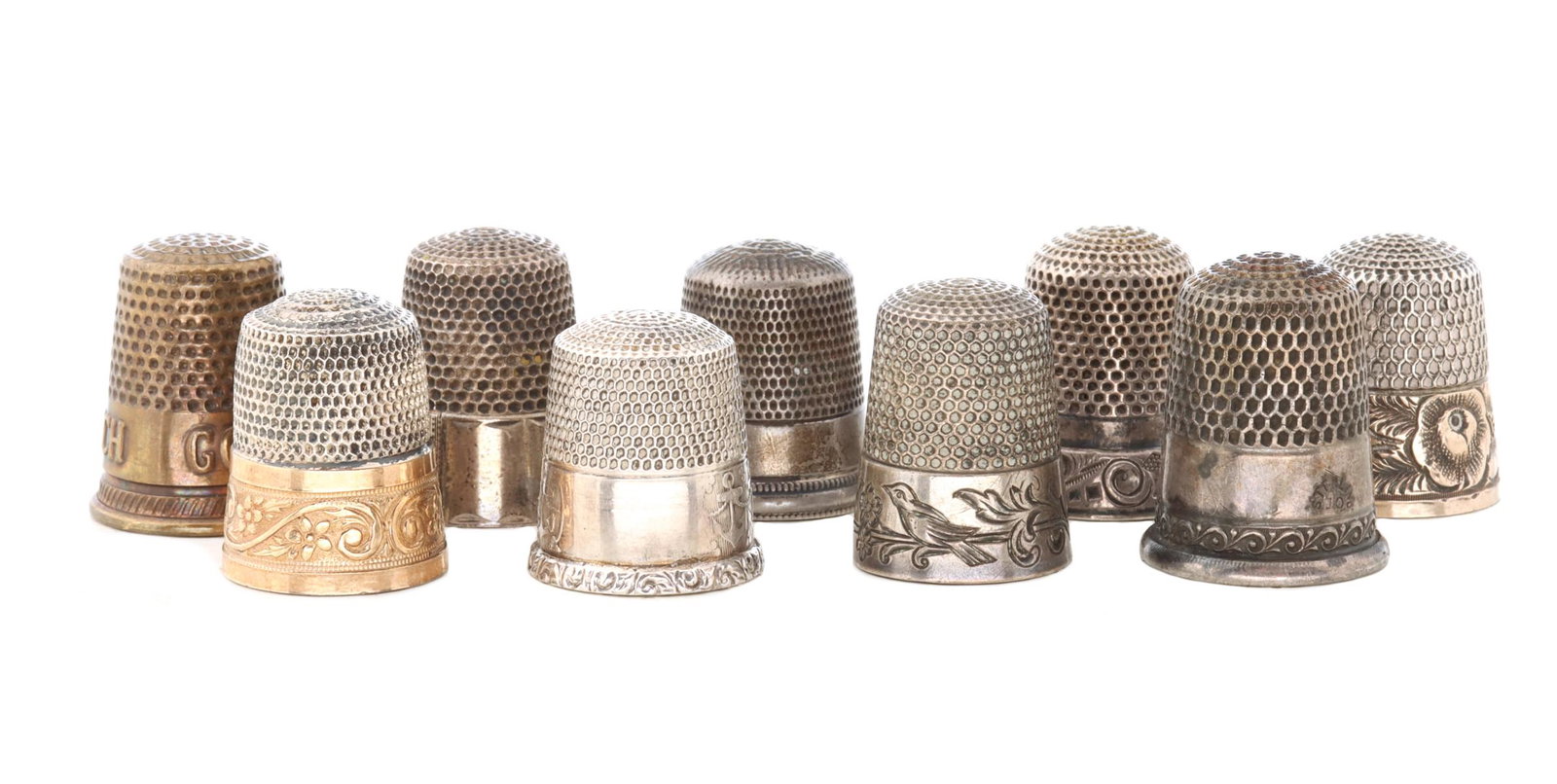 A COLLECTION OF ANTIQUE STERLING SILVER THIMBLES: The group as shown, most with markings, one with gold band, examples with hand engraving and stamped designs, one is brass. Total sterling weight 1.08 ozt. We happily provide seamless in-house packing