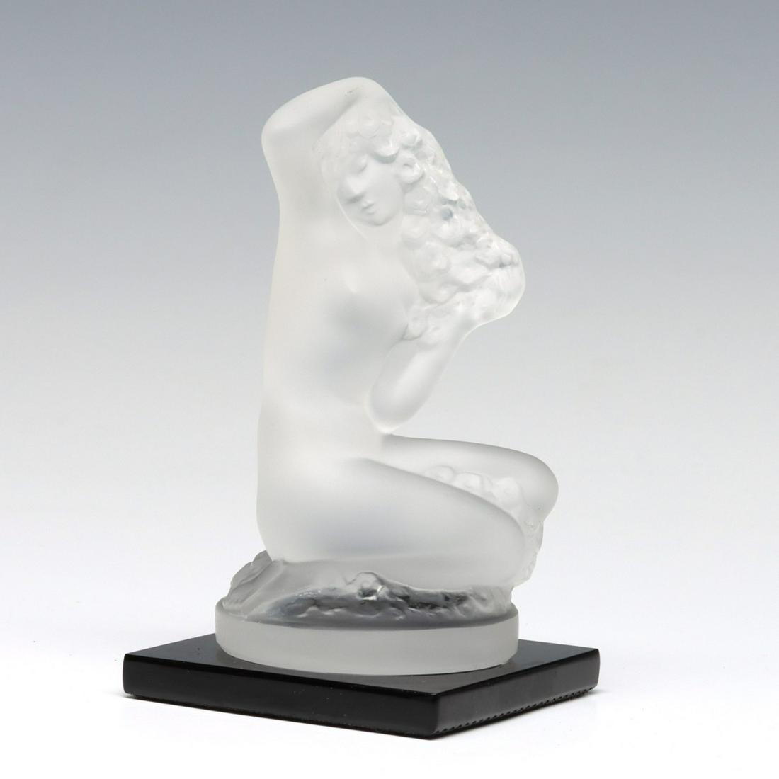 A FRENCH ART GLASS STATUETTE SIGNED LALIQUE: The frosted crystal figure of a crouching nude with garland titled FLOREAL and signed Lalique, France mounted on black glass base with paper label as shown. Measures 3.5 inches. We happily provide sea