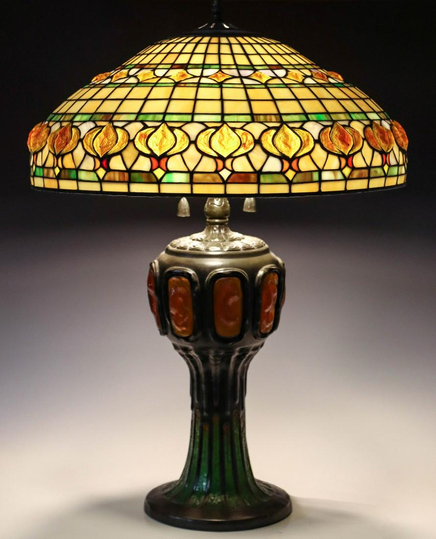 A LATE 20TH C TABLE LAMP WITH TURTLEBACK SHADE AND BASE: The reproduction inspired by Tiffany Studios incorporates a geometric pattern shade with turtleback glass enhancements, the patinated bronze base with turtleback and other glass mosaics. Measures 28 x