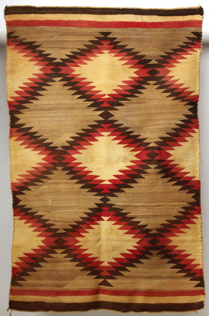 A NAVAJO GANADO TRANSITIONAL RUG WITH BANDED ENDS: The field of serrated diamonds and half diamonds bracketed by banded ends, early 20th century. A reproduction storm pattern weaving is included. Measure 64 x 40 and 82 x 52 inches. We happily provide 