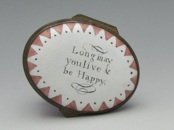 18TH CENTURY BATTERSEA ENAMEL BOX W/ MOTTO: Oval box with light purple enamel, white lid with painted design and message 'Long may you live & be Happy.' Solid white interior, mirrored inside lid. Measures 1 x 1-1/2 x 1-1/4 inches.