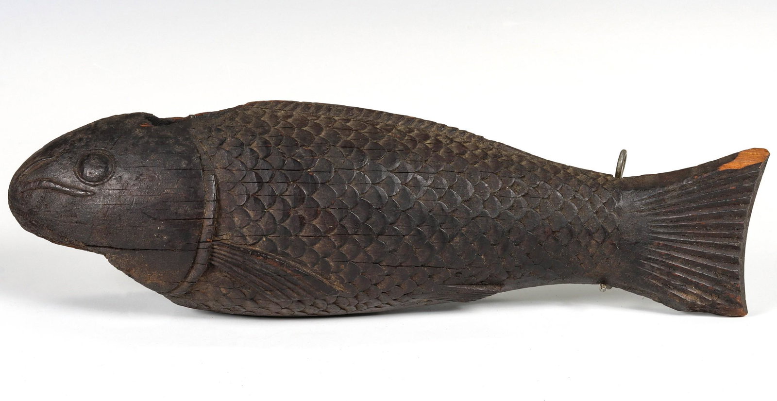 A JAPANESE MEIJI PERIOD CARVED WOOD KOI JIZAI KAGI: The darkly patinated carved wood figure of a good fortune Koi fish that hung above the fire area in a Japanese home throughout the 19th century, or earlier. Measures 15 x 4 inches. We happily provide 