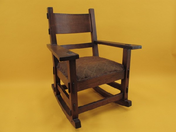 A MISSION ROCKING CHAIR WITH MORTISED CONSTRUCTION: Walnut, great style, many mortised joints that extend past arms and backs. Old woven seat with springs and three slats. Measures 34 x 27 x 27 inches overall.