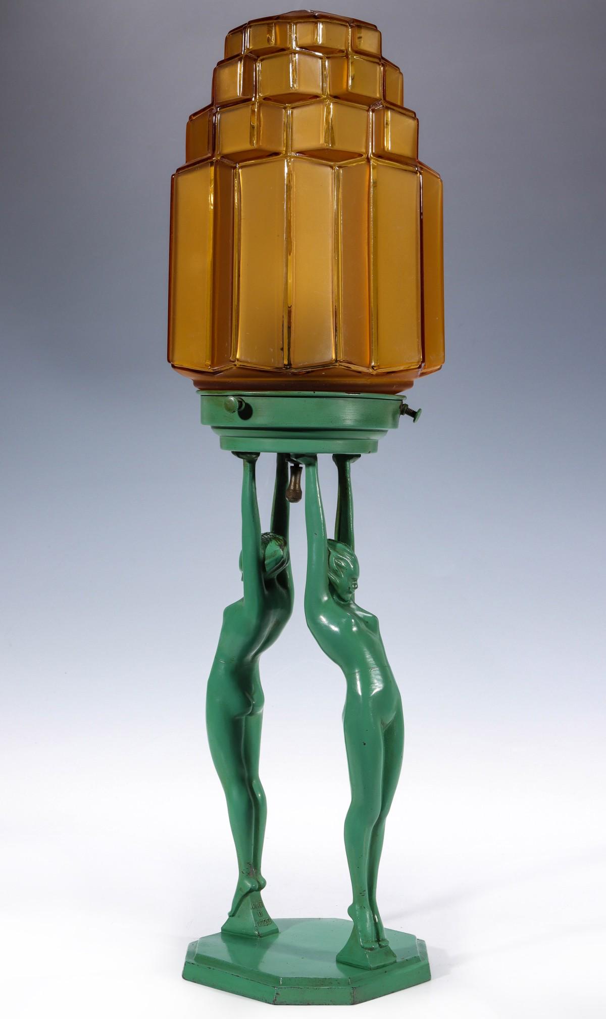 A FRANKART ART DECO LIGHT SUPPORTED BY NUDE FIGURES: The design by Arthur von Frankenberg (1889 - 1950) for Frankart, model L211 featuring two tip-toe nudes in original green enamel finish holding aloft a stepped hex shape amber globe with frosted groun