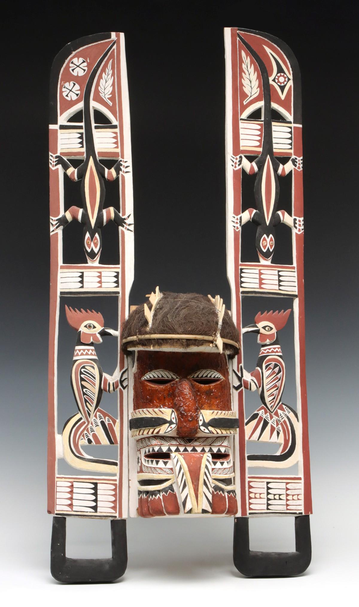 A MALANGAN CARVED WOOD HEADDRESS NEW IRELAND: The elaborate carved wood headdress comprised of a central mask flanked by tall openwork carvings with lizards and birds is decorated in natural earth pigments and embellishment of fiber as hair. Meas