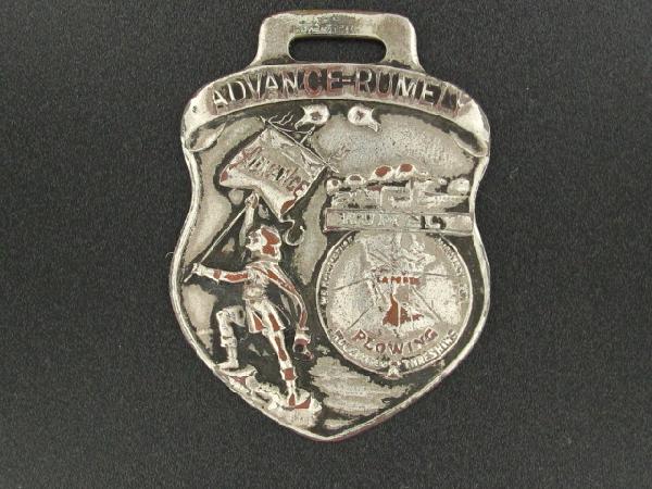 RUMELY OIL PULL TRACTOR ADVERTISING WATCH FOB: Die struck, 'Advance Rumely' and image to obverse, reverse with raised lettering, 'Rumely Oil Pull Tractor, Guaranteed to burn kerosene at all loads under all conditions, Advance-Rumely Thresher Co.,