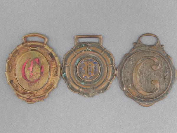 ANN ARBOR HAY PRESS ADVERTISING & INITIALED WATCH FOBS: Three total; all die struck, different designs. Ann Arbor Hay Press advertisment, measures 1.75 x 1.25 inches, with 'O' in translucent red enamel obverse. Other two different designs, one with stylize
