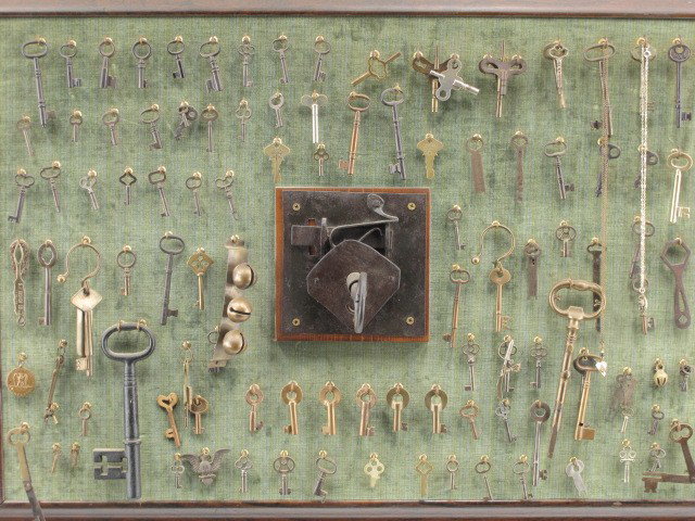 AN ANTIQUE KEY AND LOCK COLLECTION INCL RAILROAD: A display board with central forged iron lock and key along with a number of unusual pieces, two marked Railroad keys, one for SANTA FE and one for T RY, overall measurements of 24 x 33 inches