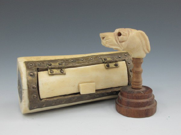 CARVED IVORY SNUFF BOX AND DOG HEAD: An ivory box with hinged lid and metal trim, ends with soldered buttons, measures 4 inches long, currently contains buttons. Also a nicely carved dog's head on wooden pedestal stand, measures 2.5 inch