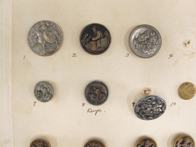 ANTIQUE FIGURAL METAL JASPERWARE & PAPERWEIGHT BUTTON: Twenty-five figural metal buttons depicting Neptune, Buster Brown, Osiris and Horus, Aeneas with Shield, and more, sizes from 1.625 to .5 inches. One Wedgwood blue Jasperware oval button depicting Mod