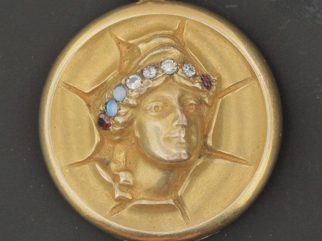 AN ART NOUVEAU LOCKET CIRCA 1900: Gold-filled with four diamonds, two opals and two garnets measuring 1.25 inches diameter. Provenance: collection of Camille Grace, published page 135, plate III-77, Answers to Questions About Old Jewe