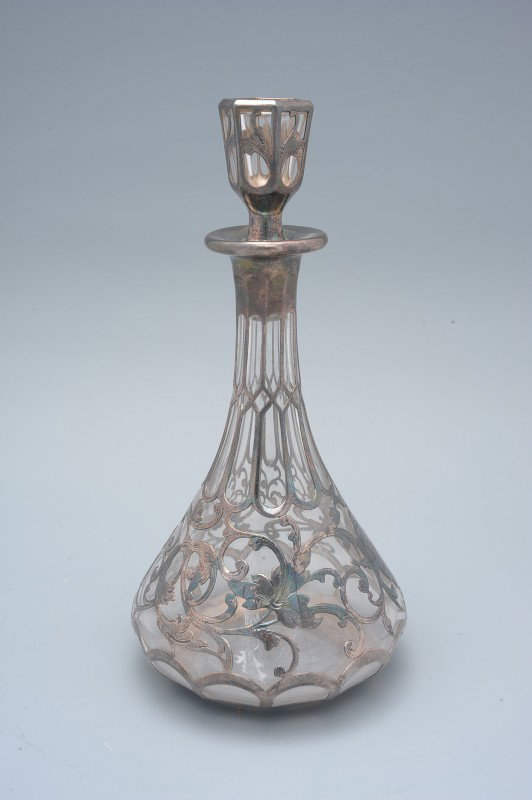 A GORHAM STERLING OVERLAY COLOGNE BOTTLE: A cut and polished bottle with numbered stopper and base, sterling silver overlay, signed Gorham and #S2062. Measurements of 8.25 inches high and 4 inch diameter base.