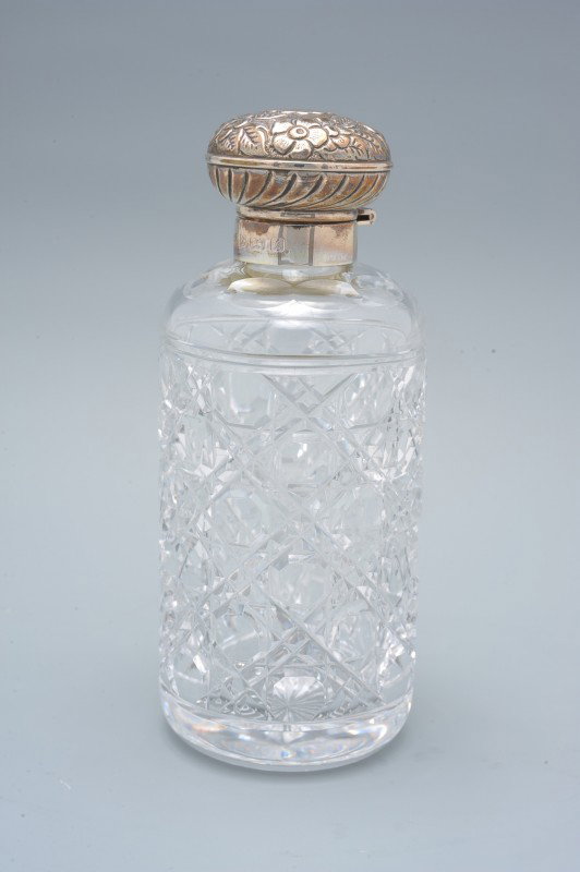 A BIRMINGHAM SILVER AND CUT GLASS COLOGNE BOTTLE: A repousse' and hallmarked sterling silver hinged cover with stamped British hallmarks for sterling, Birmingham and a date mark that appears to read 1897 but is not conclusive.