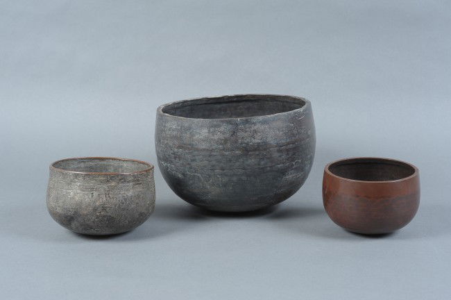 THREE JAPANESE TEMPLE BELLS: Two bronze bells without inscription or decoration beyond the typical tooling marks. A third bell with overall engraved decoration and a dull silver-colored coating or plating. Measurements of 7.5" x