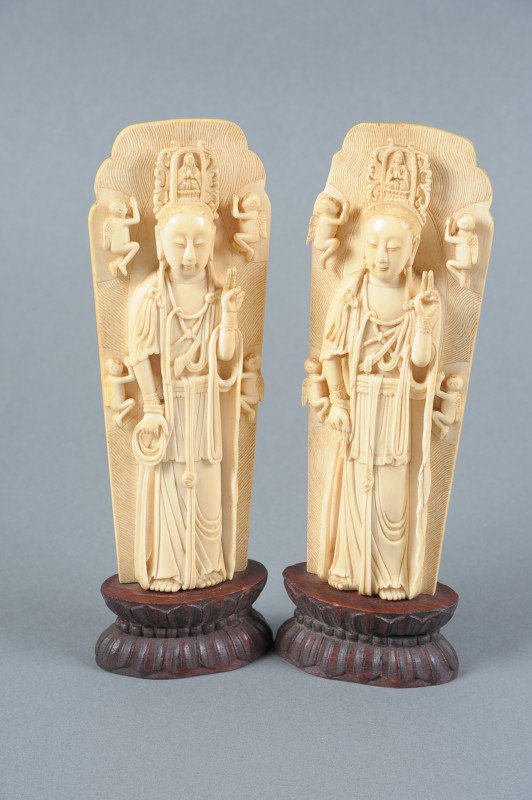 CHINESE CARVED IVORY BUDDHIST DEITIES GUANYIN: A pair of Chinese carved ivory depictions of the Buddhist deity Guanyin surrounded by a mandorla with relief carving of babies mounted on carved lotus base, 20th century, measures 9.25" x 3"