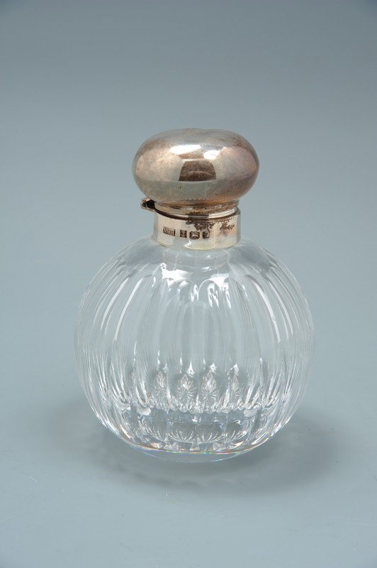 TWO CUT GLASS COLOGNES W/BIRMINGHAM STERLING SILVER: A 5" x 3.5 inch cut glass bottle with cut panel sides and A sterling silver cover bearing full hallmarks for Birmingham and maker's mark of MMH. Plus a second bottle with Birmingham sterling silver co