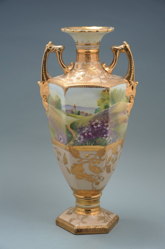 A BOLTED NIPPON URN WITH CHIP: A 15" x 7.25" green mark Noritake Nippon two-piece bolted vase with a hand-painted landscape view and gold elements.