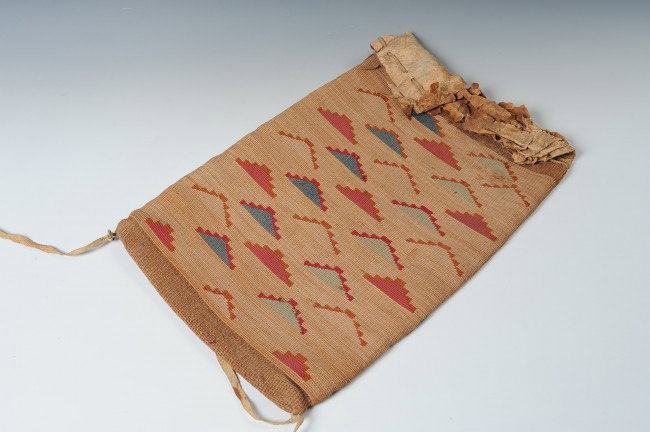 A NEZ PERCE CORN HUSK BAG: Woven with dyed corn husk to create floating designs on both sides, native tanned leather top with draw string closure. Measures 20 x 13 inches.