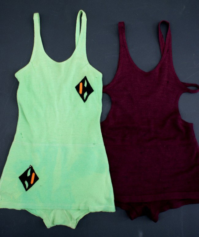 TWO VINTAGE WOOL OVER THE SHOULDER SWIMSUITS: Includes a burgundy suit, and lime green with sewn emblems on chest and skirt.
