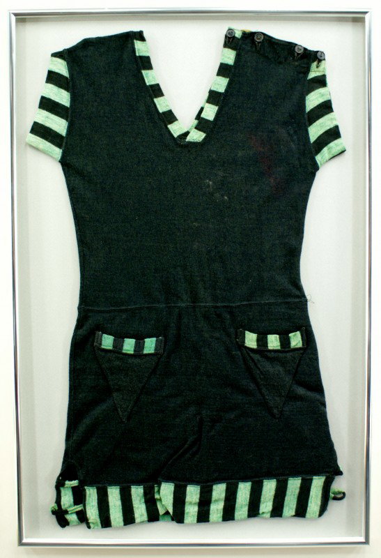 VINTAGE WOOL SWIMSUIT COVER-UP: Navy blue swimsuit cover-up with a 4-button shoulder and striped green and navy accents on the cap sleeves, v-neck, two v-shaped pockets and hem. Measures 33 x 21 inches in a 36 x 24 inch frame. Nicel