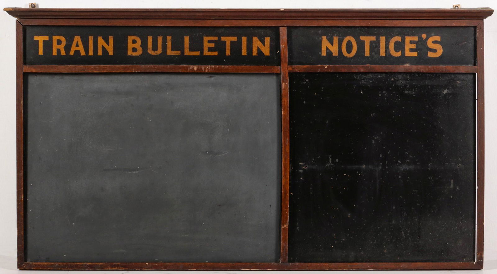A CIRCA 1900 OAK 'TRAIN NOTICES' BOARD: The wall hanging board with crown molding over the original hand painted inserts is divided into two sections: one for TRAIN BULLETIN and for NOTICES. Measures 32.5 x 60 inches. Please be aware that t