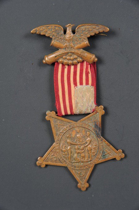 A GAR MEMBERSHIP MEDAL: Die struck bronze eagle atop cannons and cannonballs, inverted GAR star badge, double sided, suspended by restitched US flag (star field in lower right corner). Measures 3.25 x 2 inches.