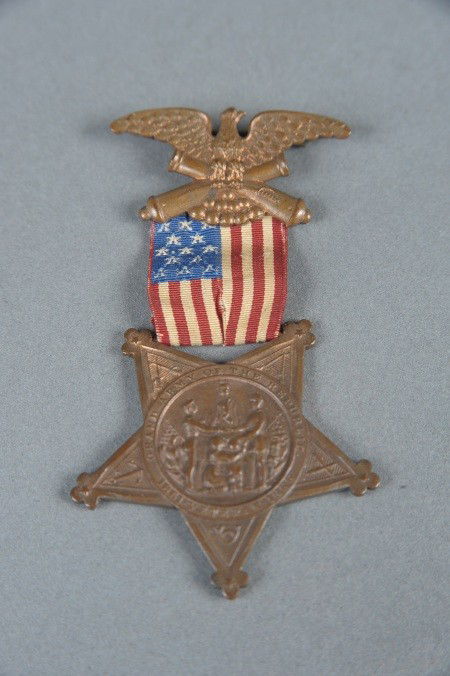 CIVIL WAR GAR VETERAN MEDAL: Fine die struck bronze eagle/cannon/cannon balls pinback brooch, marked 'Pat. May 4, 1886, June 22, 1886' on the reverse. Woven US flag ribbon and inverted GAR star medallion. Measures 3-1/8 x 1-3/4 i