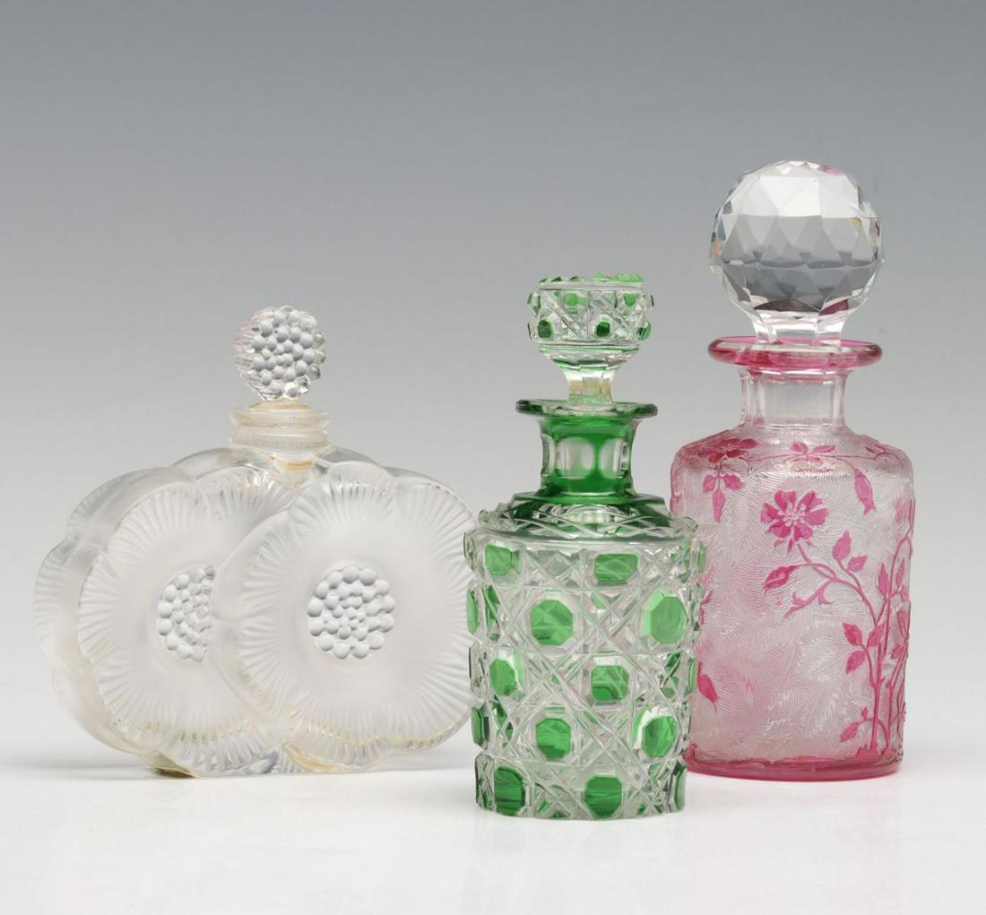 FRENCH CAMEO, BOHEMIAN AND LALIQUE SCENT BOTTLES: The bottle with cranberry colored flowers and foliage in cameo relief Eglantier pattern by Baccarat is offered with a cased green cut to clear bottle with buttons and a Lalique Deus Fleurs bottle with