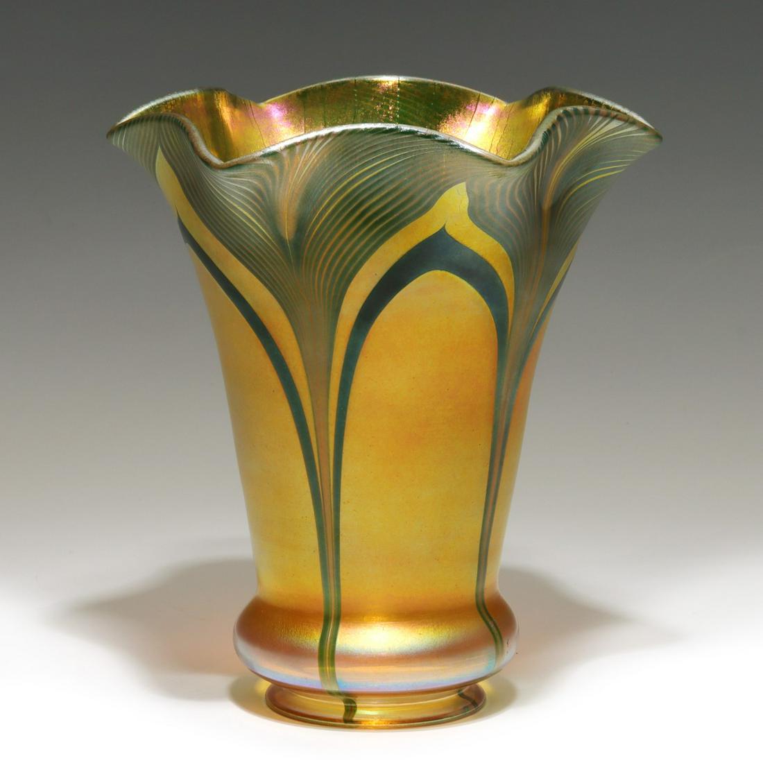 AN ELABORATE ART GLASS SHADE WITH PULLED FEATHER: The flared shade with six folds and iridescent finish is unsigned. Possible attribution to Orient and Flume. Measures 6.25 x 5.5 with a fitter size of 2.25 inches. We happily provide seamless in-house