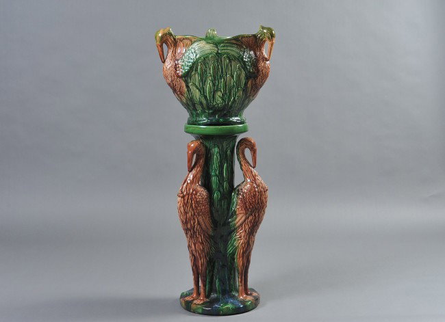 A RADFORD BIRD FIGURAL JARDINERE AND PEDESTAL: An Albert Radford art pottery jardinière and pedestal with detailed three-dimensional herons or cranes among cattails and lily pads, covered with a majolica type flowing glaze of russet, brown, green