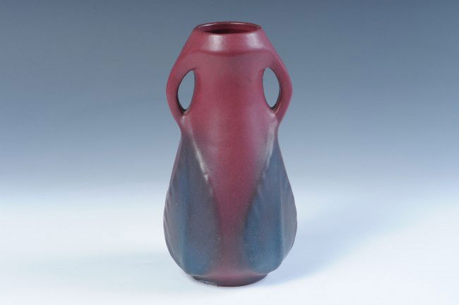 A 1920s USA MARK VAN BRIGGLE TWO HANDLE VASE: A nine inch mulberry glaze two-handled vase with deep blue leaves, USA mark circa 1922-1926, measures 9 inches.