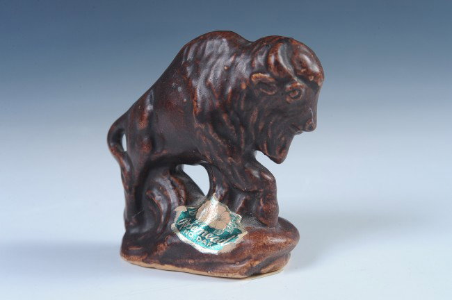 A ROSEMEADE SOUTH DAKOTA POTTERY BUFFALO: Brown glazed figure with the original Rosemeade foil label and a Rosemeade ink stamp on the bottom, measures 6 x 6.5 inches.