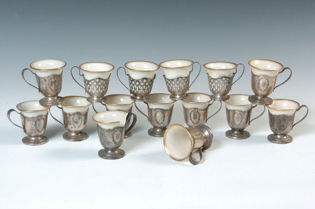 FIFTEEN LENOXCHINA AND STERLING SILVER DEMITASSE CUPS: Four pierced pattern cup frames, each marked 'Sterling 166,' eleven more with Gorham marks and 'sterling 3835,' engraved wreaths on sides. Each includes a Lennox marked porcelain insert. Silver weighs